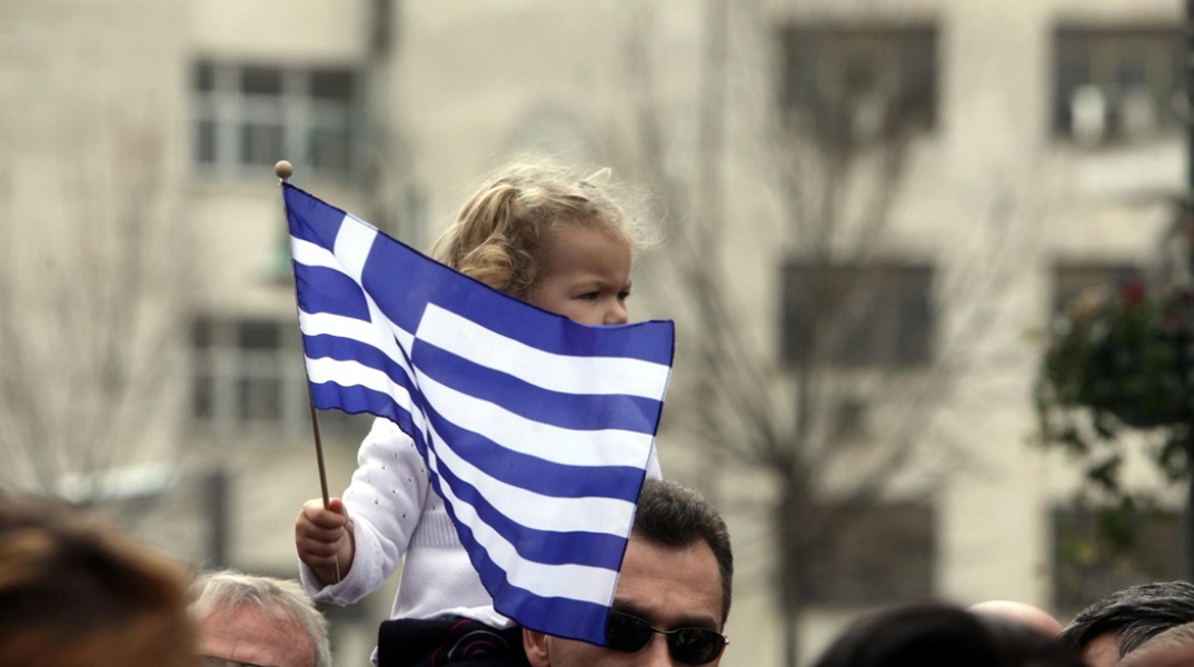 Παιδάκι με την ελληνική σημαία στους ώμους του πατέρα του