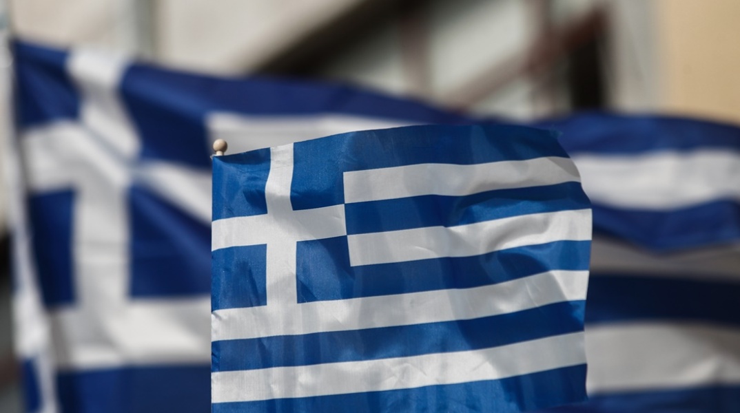 Ελληνική σημαία μπροστά από μία μεγαλύτερη ελληνική σημαία