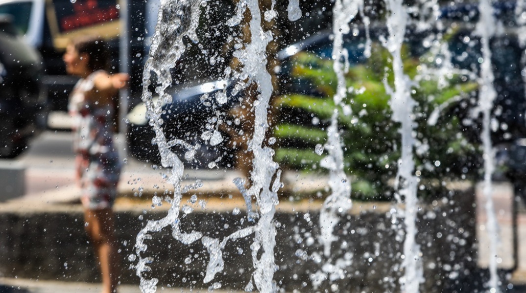 Άτομο δίπλα από συντριβάνι εν μέσω υψηλών θερμοκρασιών