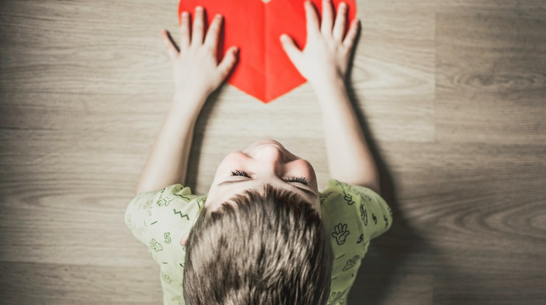 Παιδί κρατά σε επιφάνεια μία κόκκινη καρδιά - Λήψη από ψηλά 