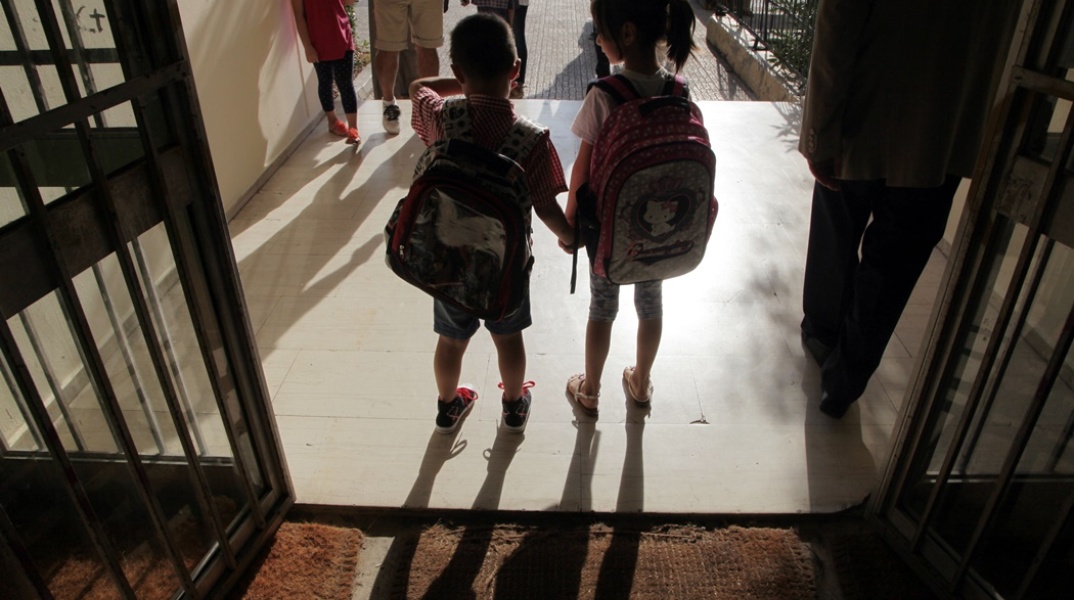 Παιδάκια πιασμένα χέρι χέρι μπαίνουν στο σχολείο τους με τις τσάντες στους ώμους