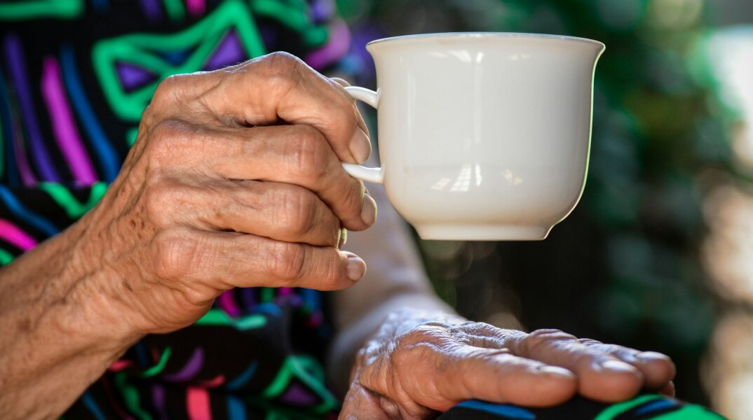 Τα χέρια ηλικιωμένης γυναίκας με φλιτζάνι καφέ