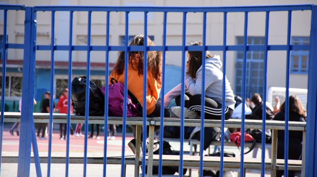 Μαθητές κάθονται σε σιδερένια κερκίδα στο προαύλιο σχολείου