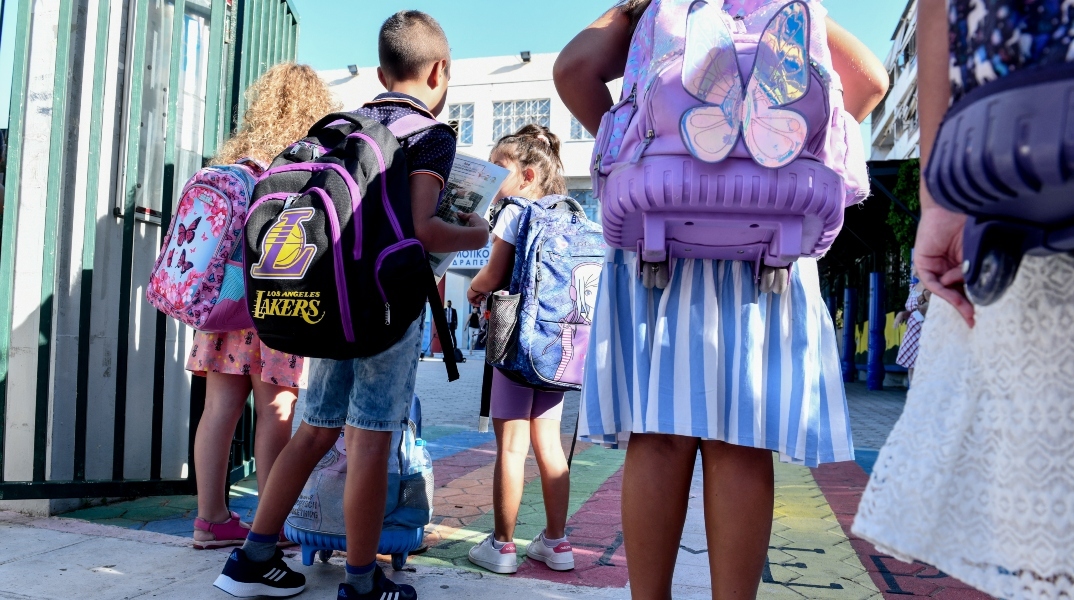 Μαθητές στο προαύλιο σχολείου με τις τσάντες τους στον ώμο