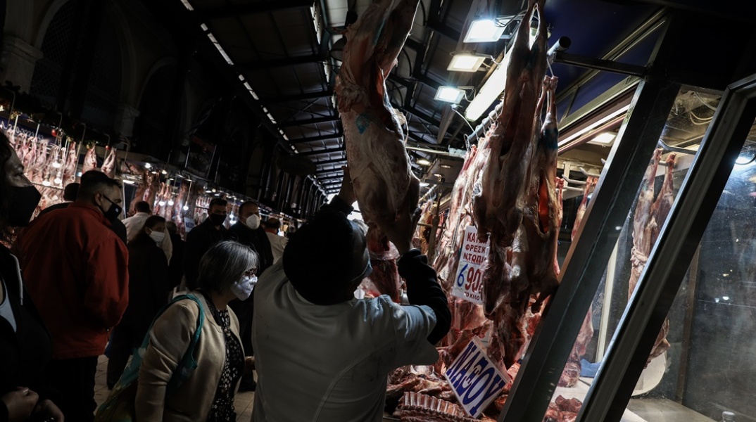 Στιγμιότυπο από κρεοπωλείο όπου εργαζόμενος ξεκρεμά αρνί από τα τσιγκέλια