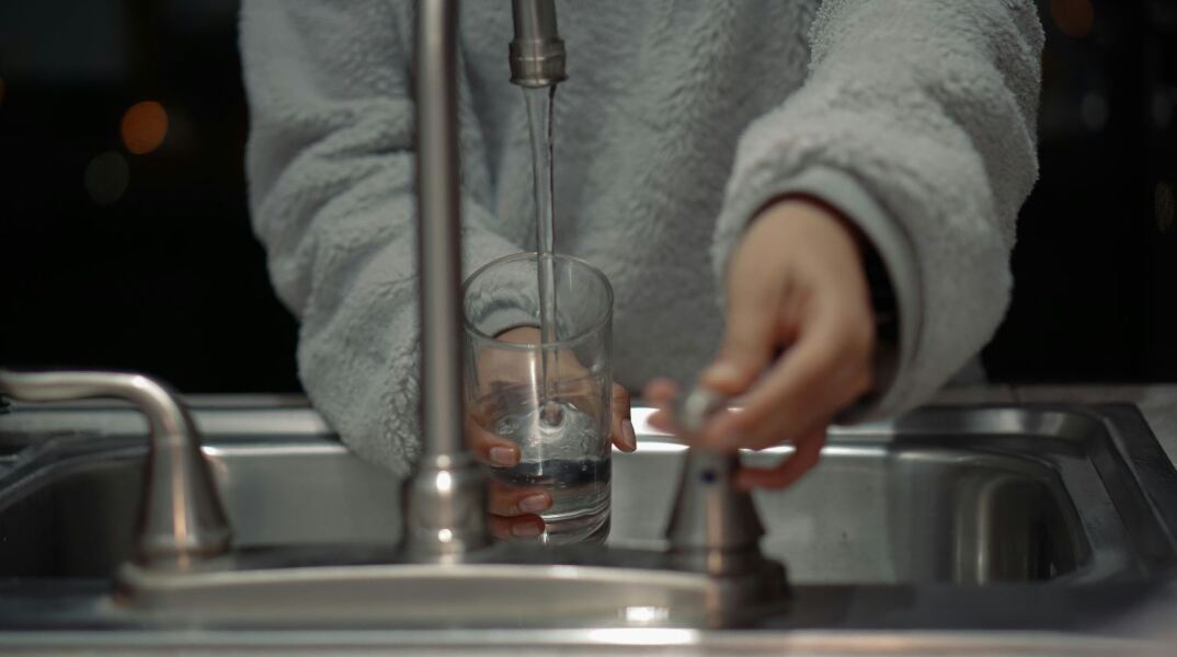 Γυναίκα βάζει νερό σε βρύση