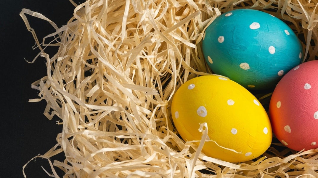 Φωλίτσα από χορτάρια και τρία αυγά βαμμένα κίτρινο, κόκκινο και μπλε βαμμένο πουά
