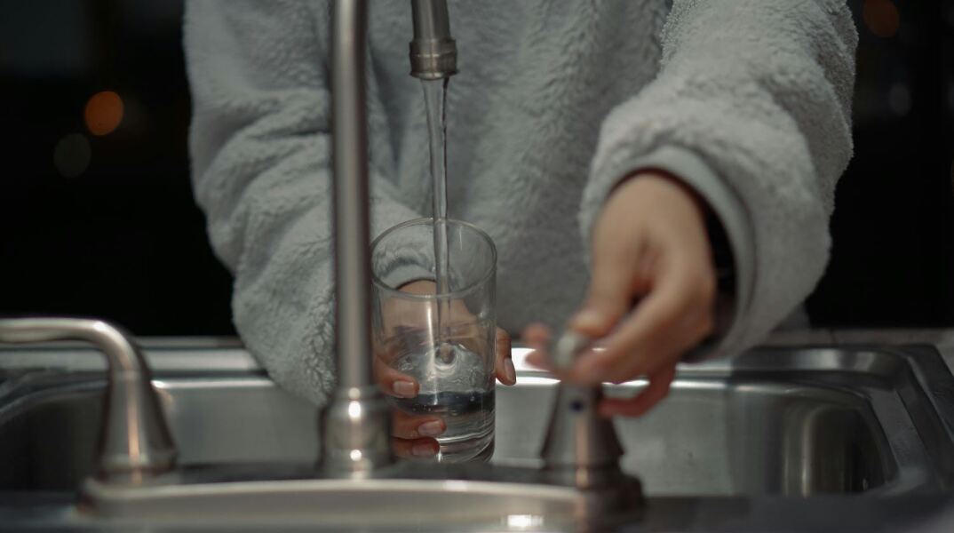 Γυναίκα βάζει νερό σε βρύση