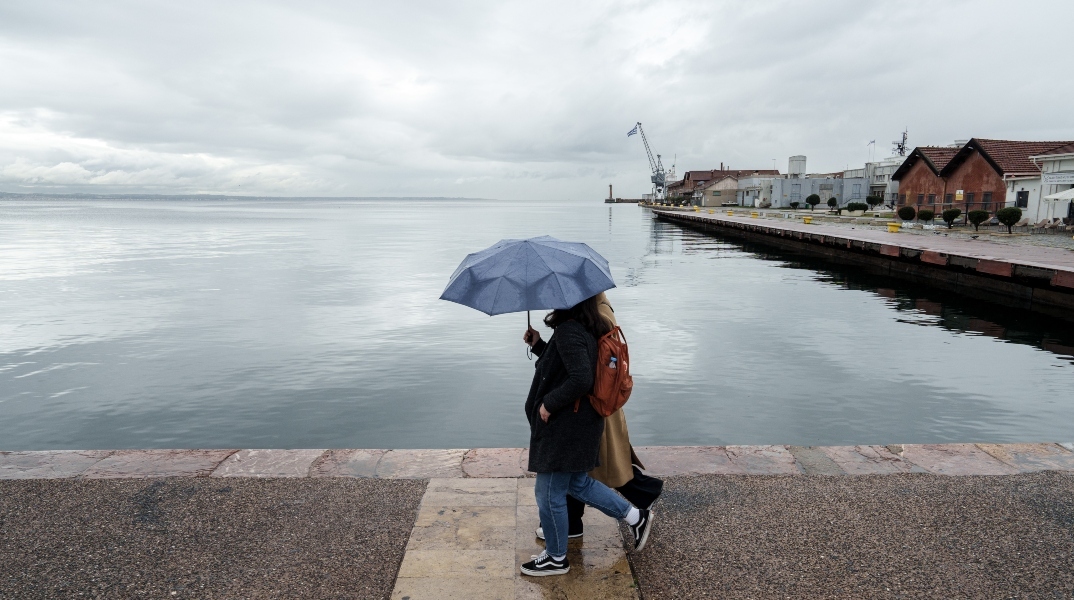 Κόσμος περπατάει έπειτα από βροχόπτωση στην παλιά παραλία της Θεσσαλονίκης