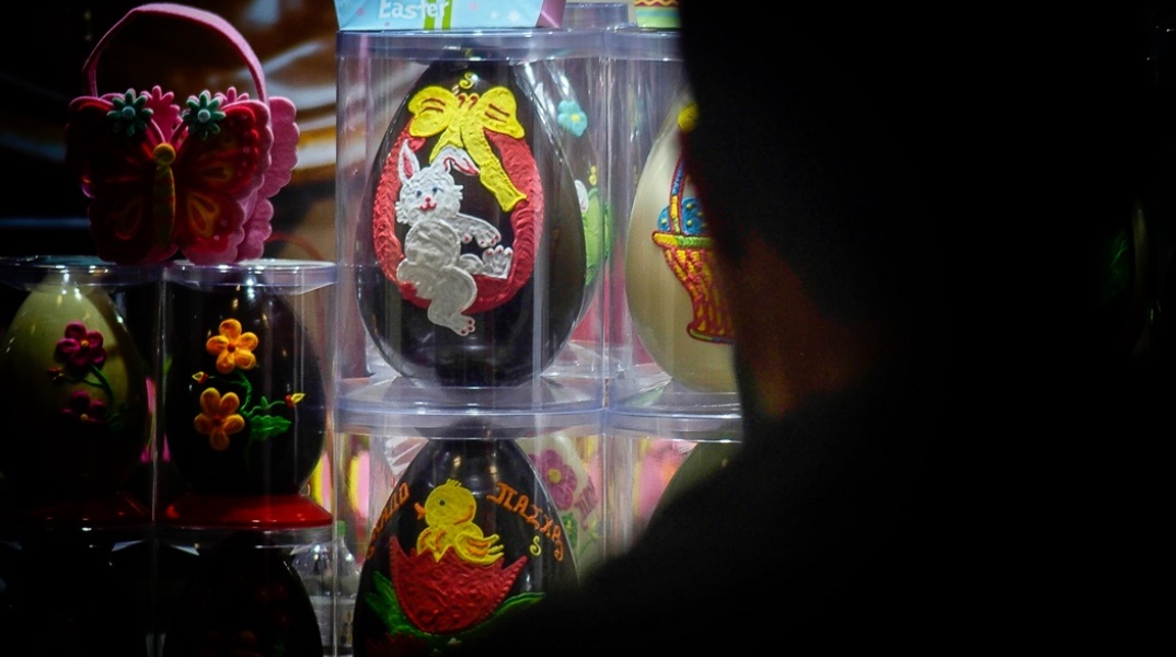 Σκιά ατόμου στα δεξιά του φακού που κοιτά βιτρίνα με σοκολατένια αυγά με φιγούρες από κινούμενα σχέδια