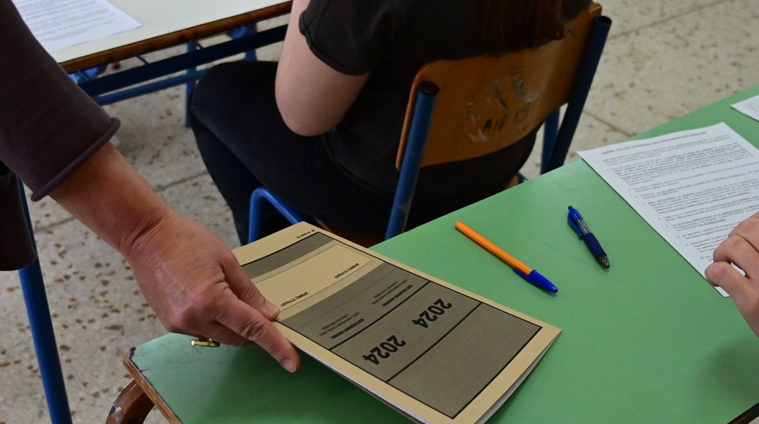 Καθηγήτρια μοιράζει τα τετράδια απαντήσεων που φέρουν στο εξώφυλλό τους το έτος διεξαγωγής των Πανελληνίων Εξετάσεων