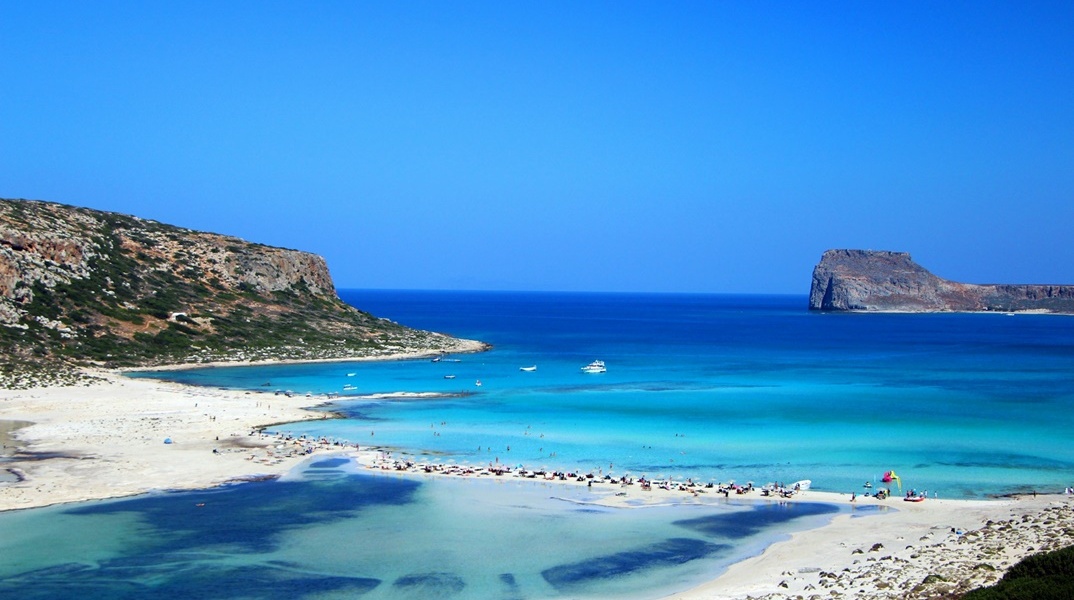 Παραλία και πολίτες με ομπρέλες ξαπλωμένοι στην άμμο δίπλα στη θάλασσα