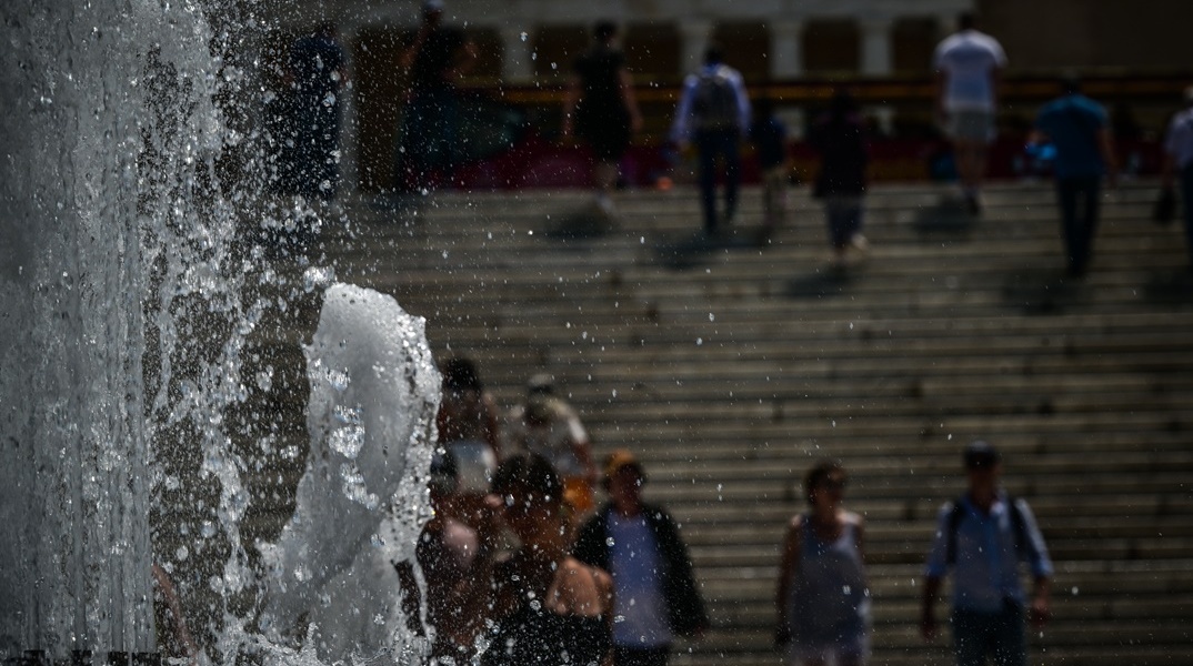 Συντριβάνι στο Σύνταγμα και πίσω πολίτες που περπατούν υπό ζέστη