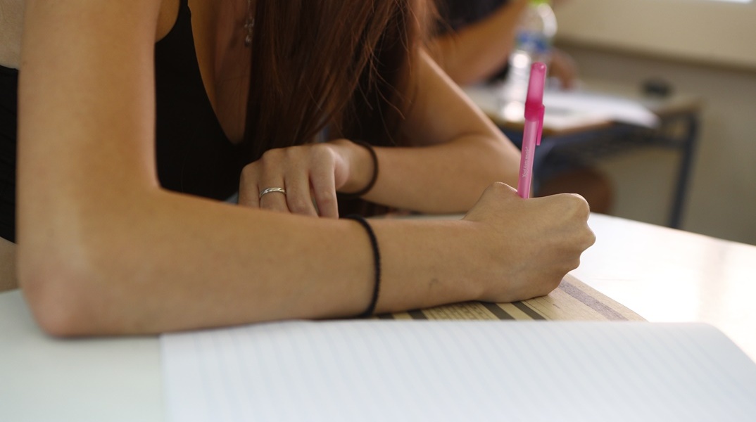 Κοπέλα γράφει στο τετράδιο απαντήσεων των Πανελληνίων 2024