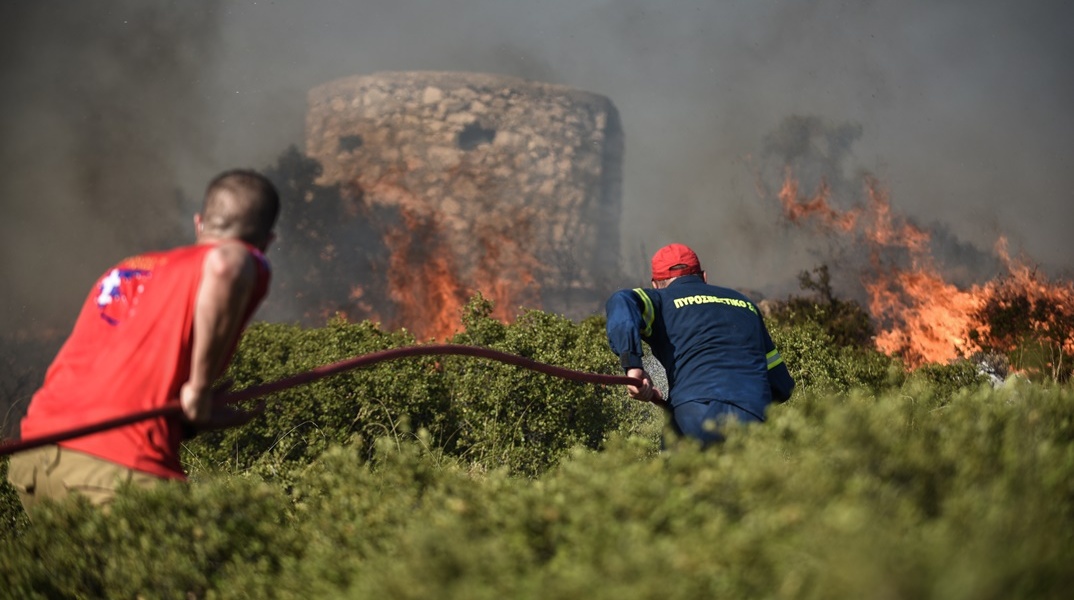 Πυροσβέστης και εθελοντής κατά τη διάρκεια κατάσβεσης πυρκαγιάς