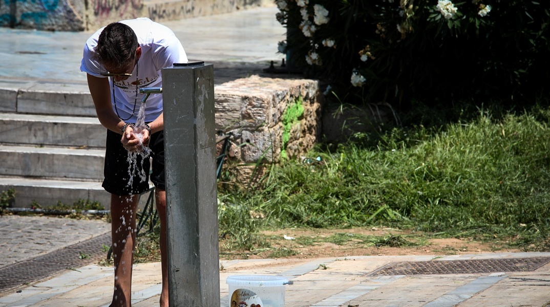 Άτομο που δροσίζει λίγο το πρόσωπό του με νερό από βρύση σε δημόσιο χώρο