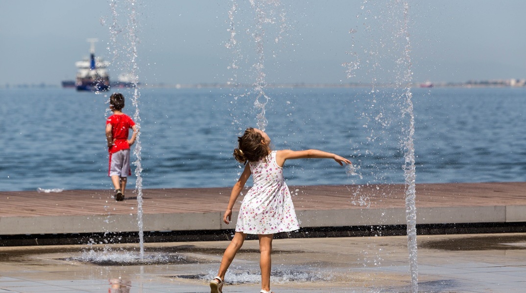 Παιδί παίζει με το νερό στο σιντριβάνι εν μέσω καύσωνα