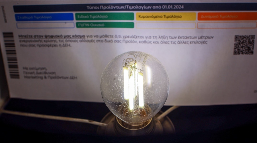 Τιμολόγιο ηλεκτρικού ρεύματος με μία αναμμένη λάμπα μπροστά