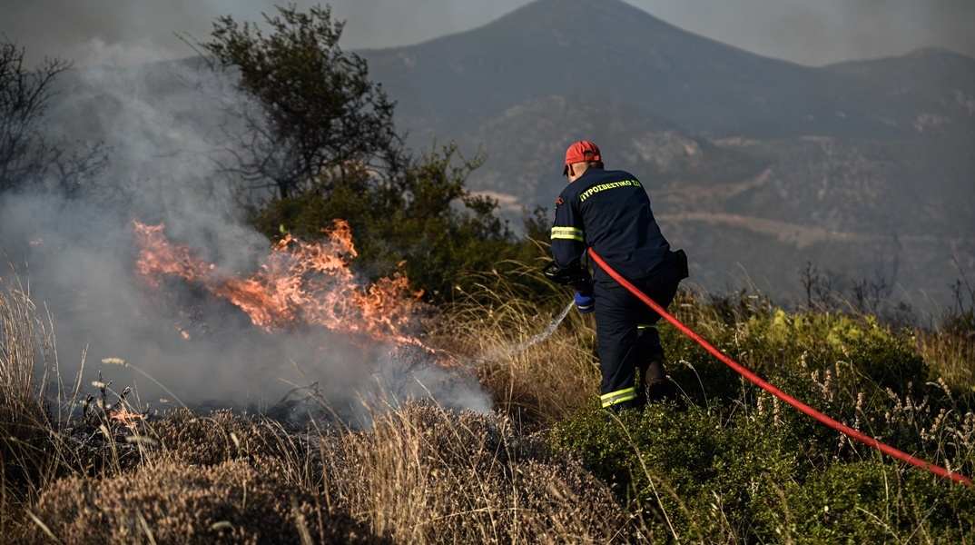 Πυροσβέστης με τη μάνικα ανά χείρας κατά τη διάρκεια επιχείρησης κατάσβεσης