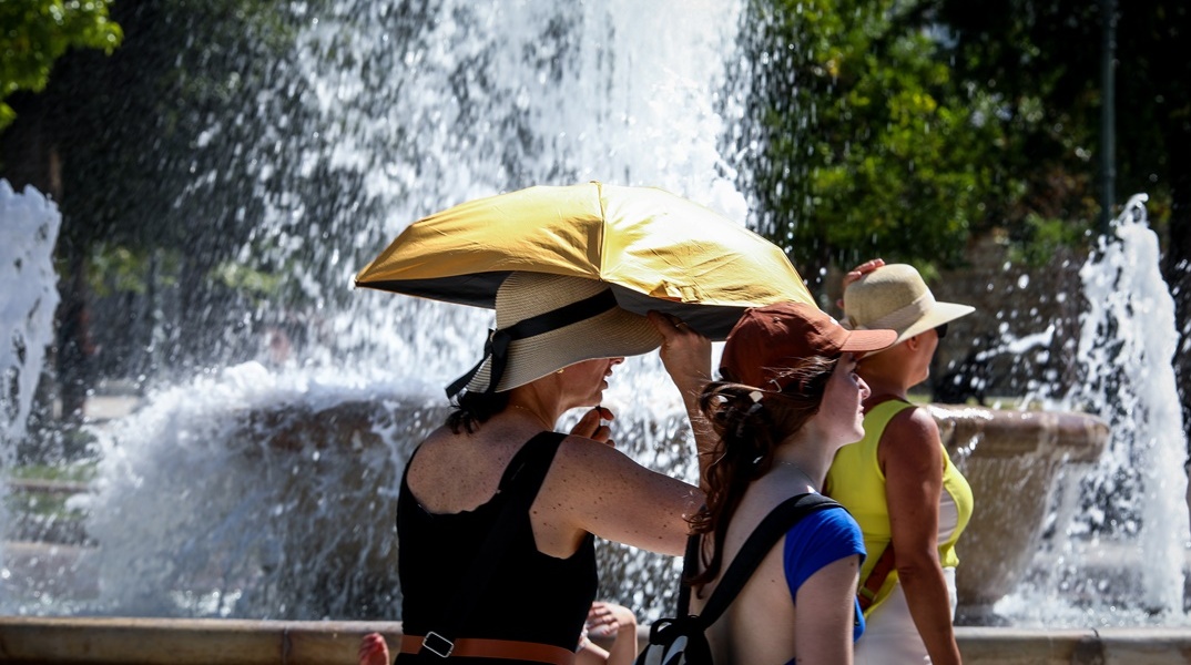 Πολίτες με ομπρέλες προστατεύονται από τον καύσωνα