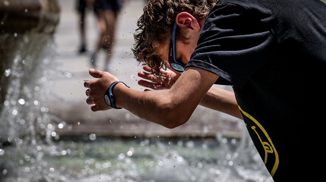 Πολίτης στο σιντριβάνι του Συντάγματος απολαμβάνει στιγμές δροσιάς