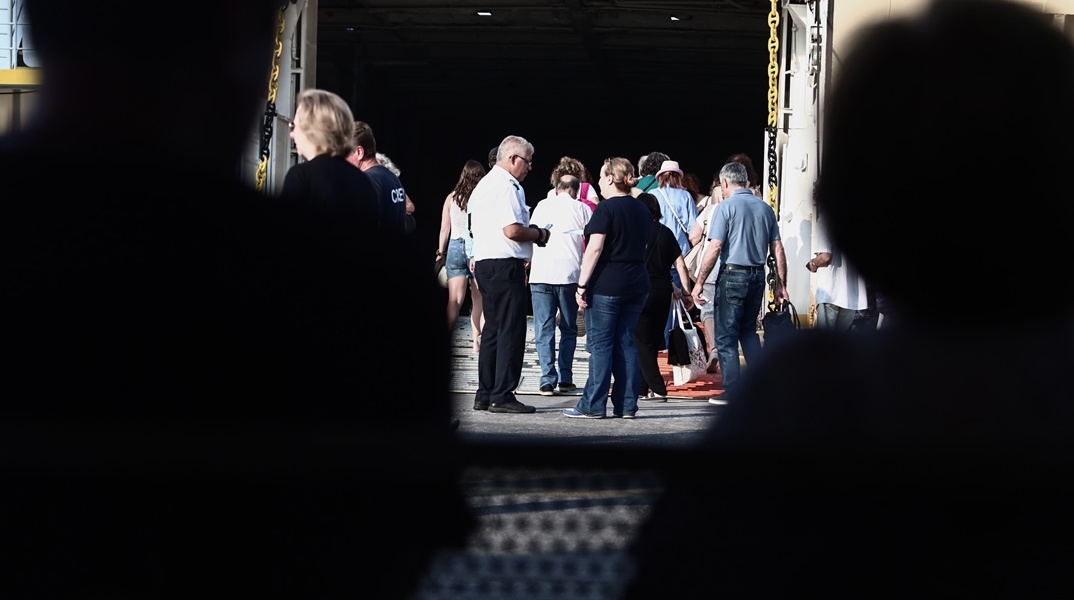 Πολίτες επιβιβάζονται σε πλοίο στο λιμάνι του Πειραιά
