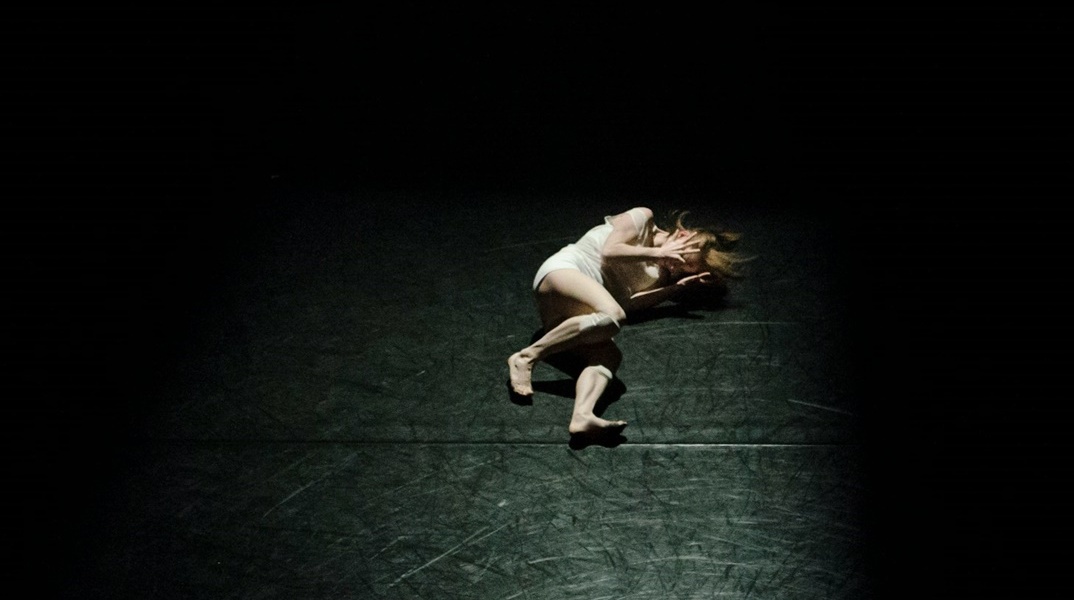 Γυναίκα σε εμβρυακή στάση σε σκοτεινό δωμάτιο με φως να πέφτει στο σώμα της