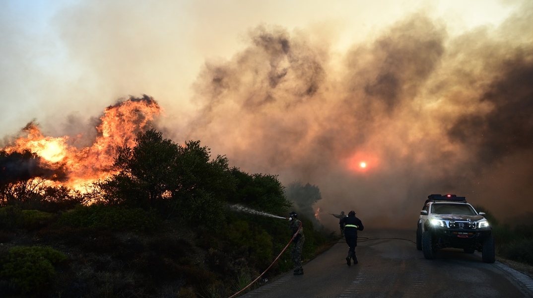 Φωτιά σε εξέλιξη και πυροσβέστης που επιχειρεί για την κατάσβεση