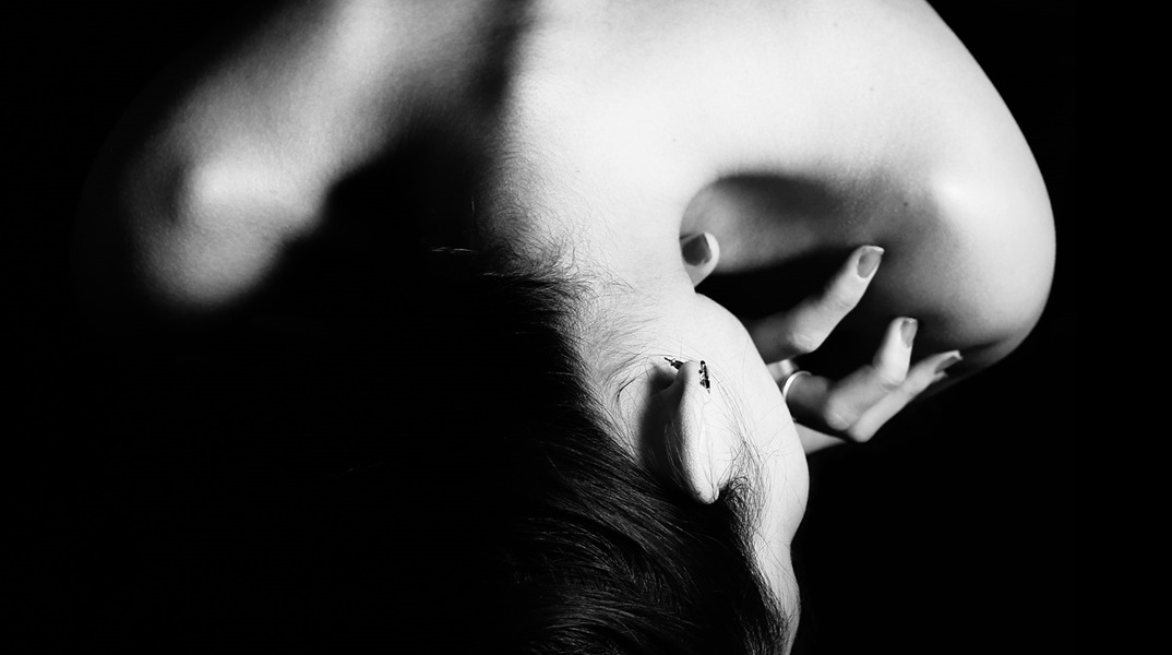 Γυναίκα που κρατά το σώμα της με τα χέρια της σε εμβρυακή στάση - Μια εικόνα που παραπέμπει σε ενδοοικογενειακή βία αφού η γυναίκα φαίνεται σε στάση άμυνας