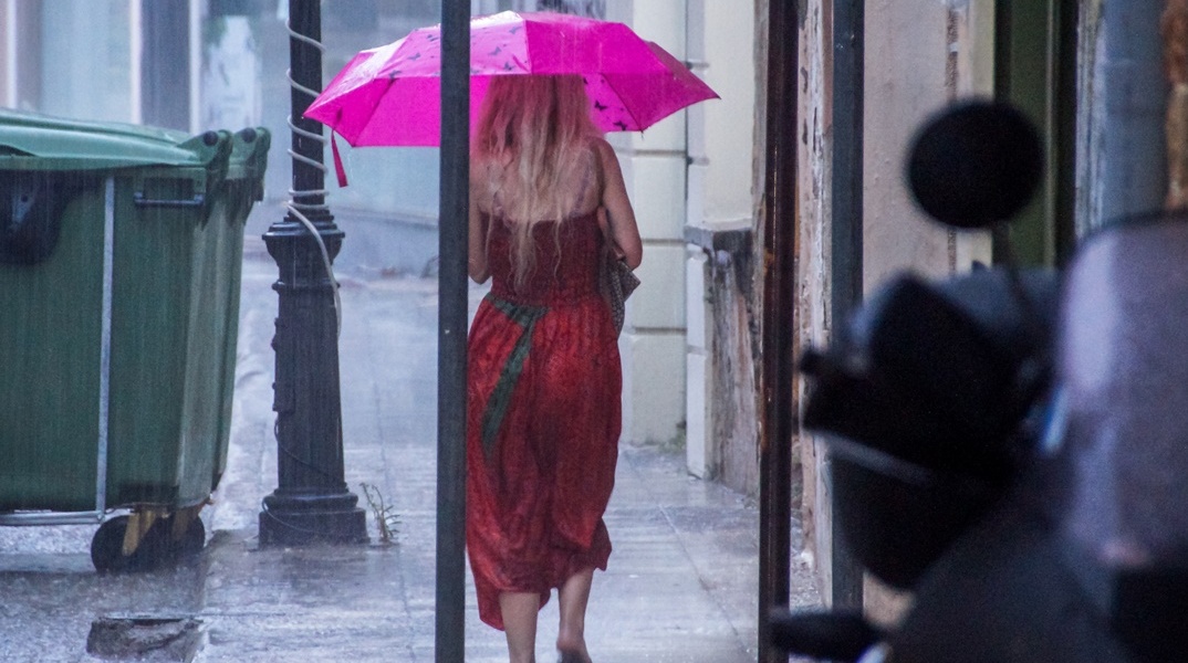 Γυναίκα προστατεύεται από τη βροχή με ομπρέλα