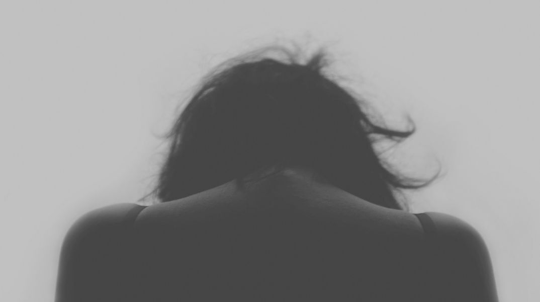 Γυναίκα με σκυμμένο κεφάλι υποδηλώνοντας πως έχει δεχτεί επίθεση