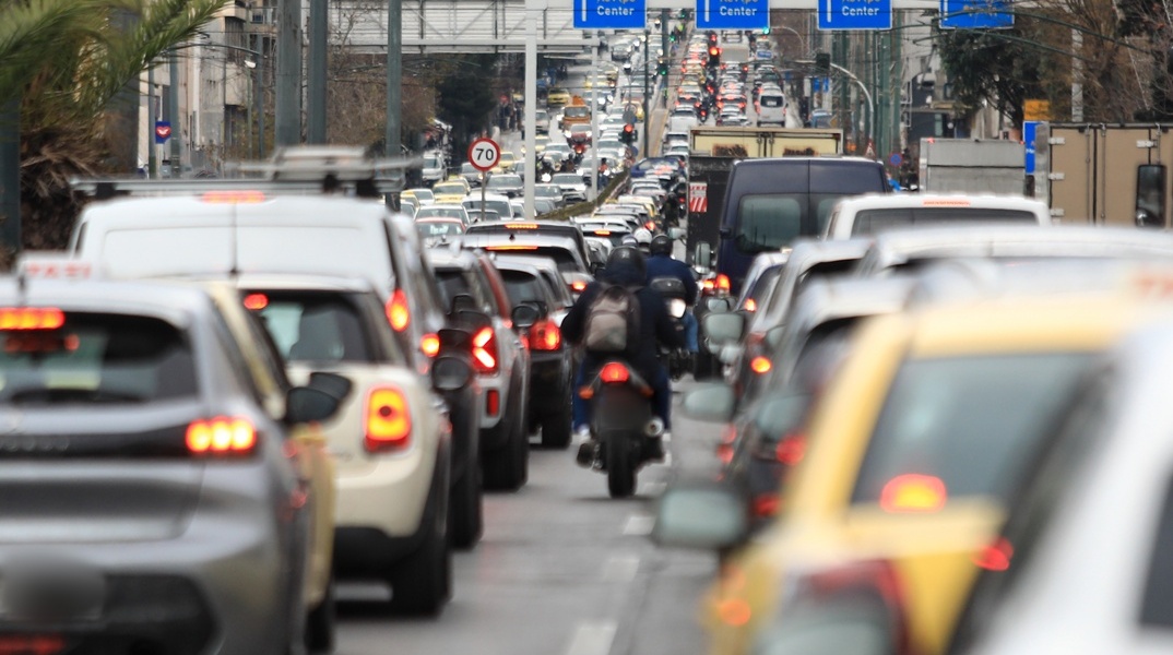 Αυτοκίνητα κολλημένα στην κίνηση και ένα μηχανάκι που περνά ανάμεσά τους