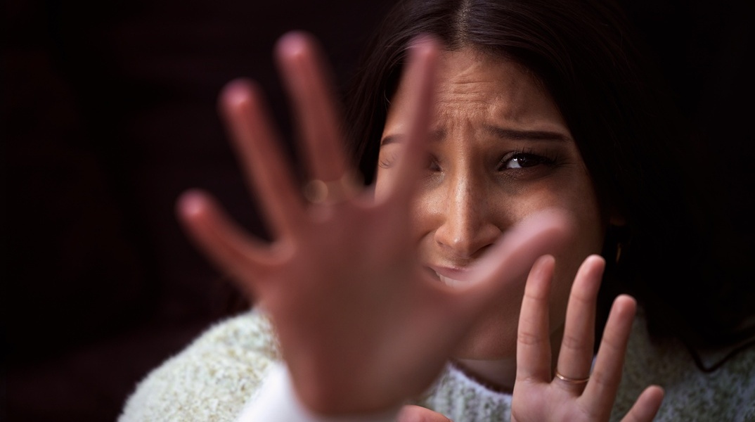 Γυναίκα με τρόμο στα μάτια προτάσσει τα χέρια της για να αντικρούσει επίθεση