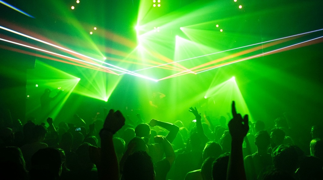 Χέρι υψωμένα σε νυχτερινό κέντρο όπου επικρατεί πράσινο φως