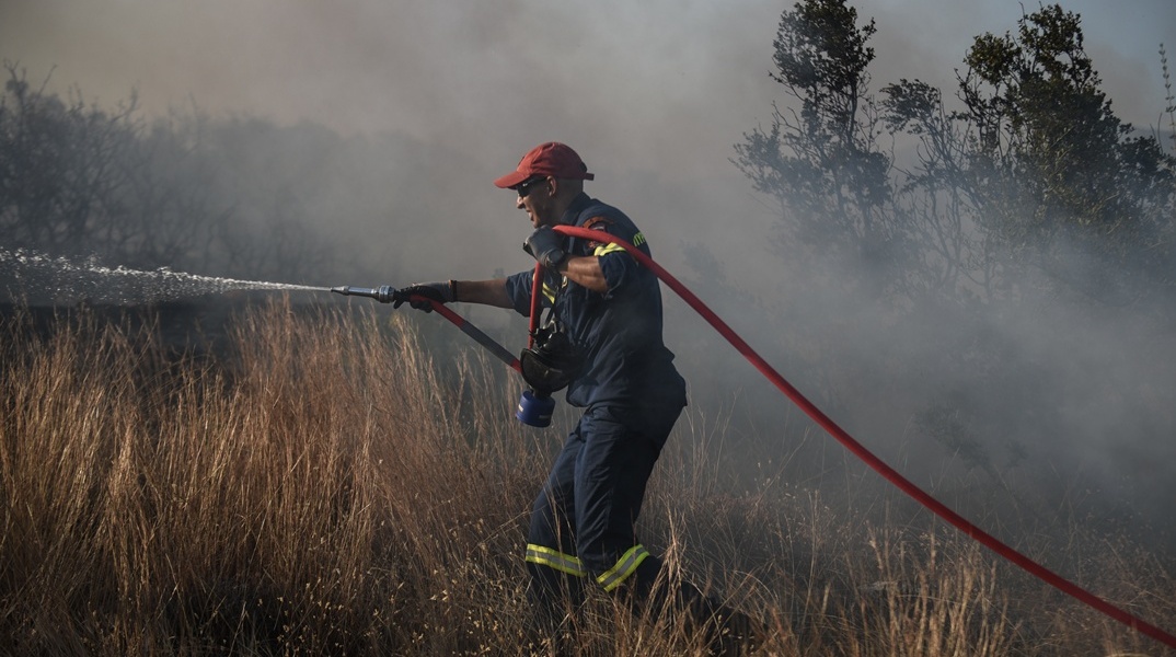 Πυροσβέστης με μάνικα ανά χείρας