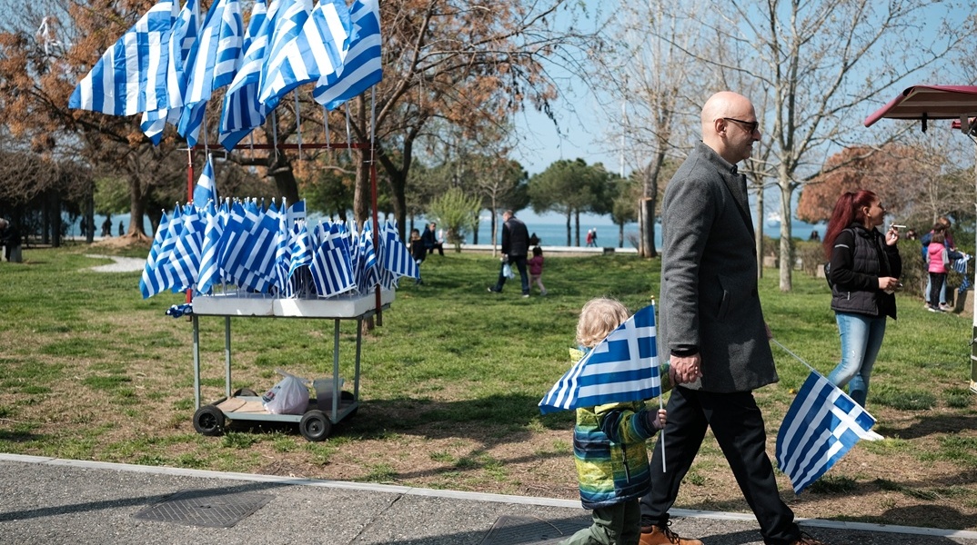 Παιδί με ελληνική σημαία και σταντ με σημαίες