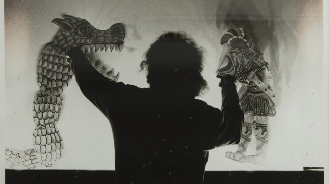 Θέατρο Σκιών και άτομο πίσω από το πανί με φιγούρες στα χέρια