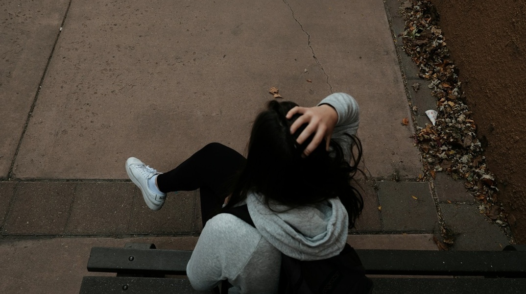 Πλάτη κοπέλας που κάθεται στο παγκάκι