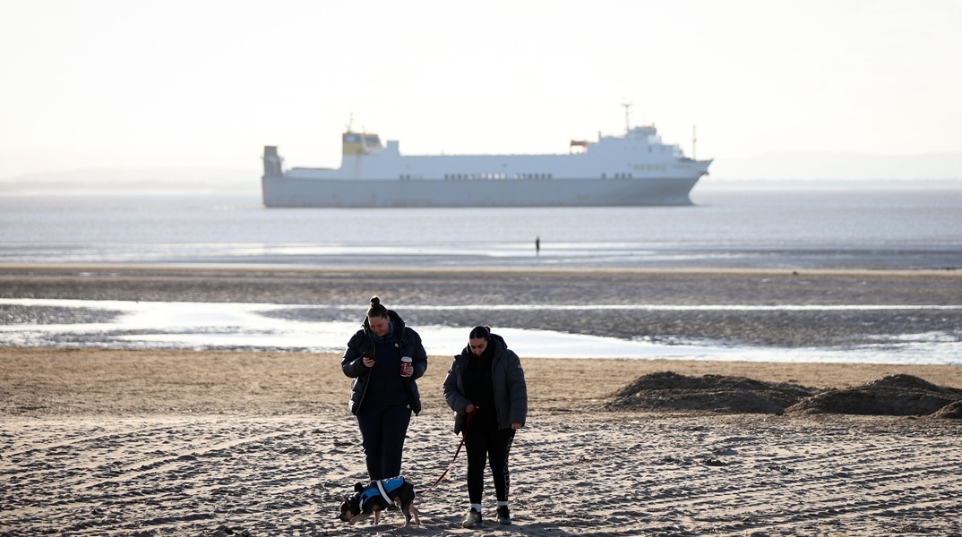 Πολίτες περπατούν σε ακροθαλασσιά όπου λόγω κλιματικής κρίσης έχει πέσει η στάθμη