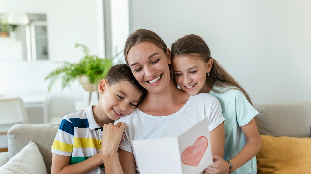 Μητέρα με τα δύο παιδιά της δίπλα της διαβάζει κάρτα