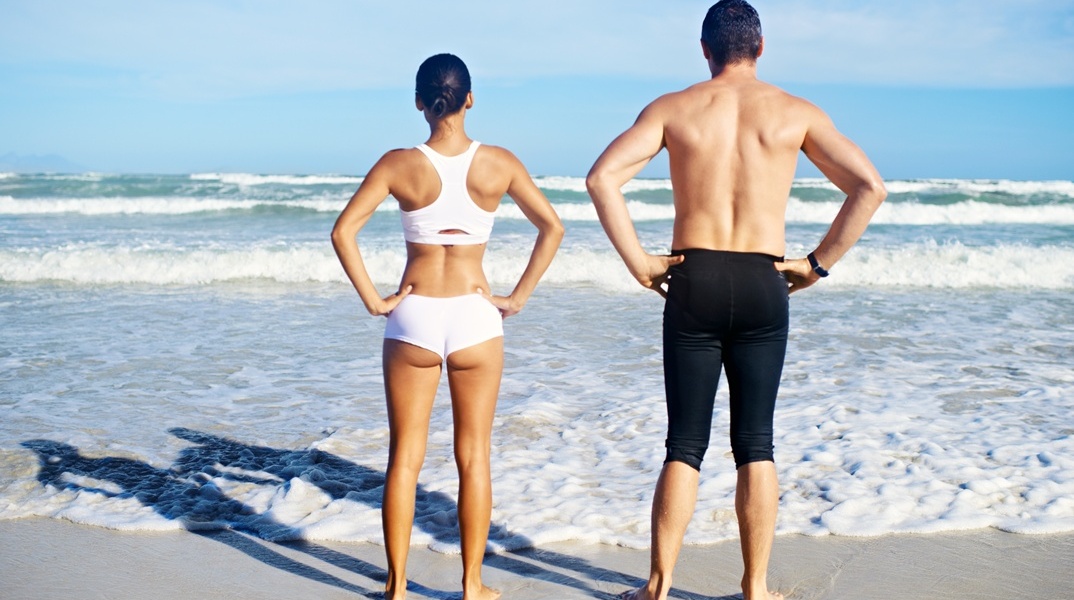 Γυναίκα και άνδρας με γυρισμένη την πλάτη στον φακό σε παραλία 