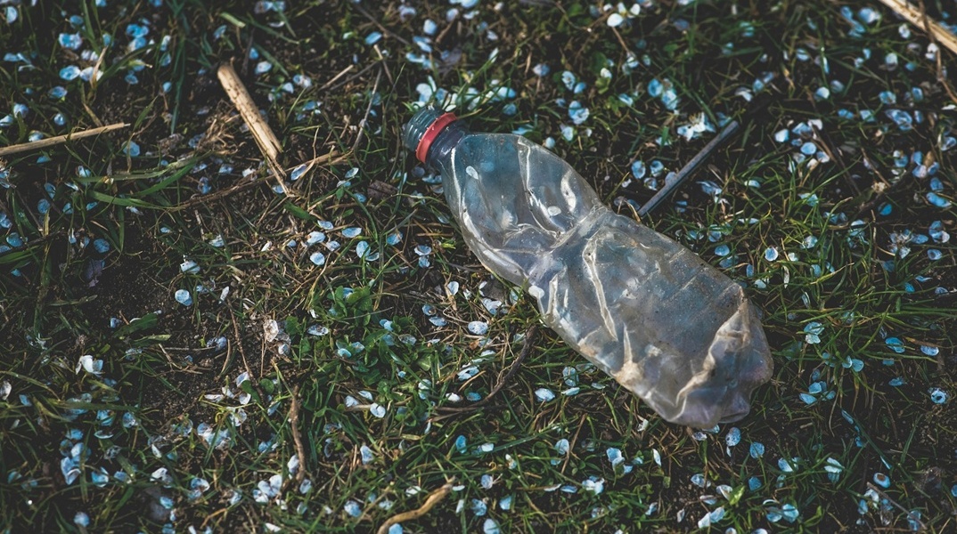 Πλαστικό μπουκάλι πάνω σε χώμα με φυτά