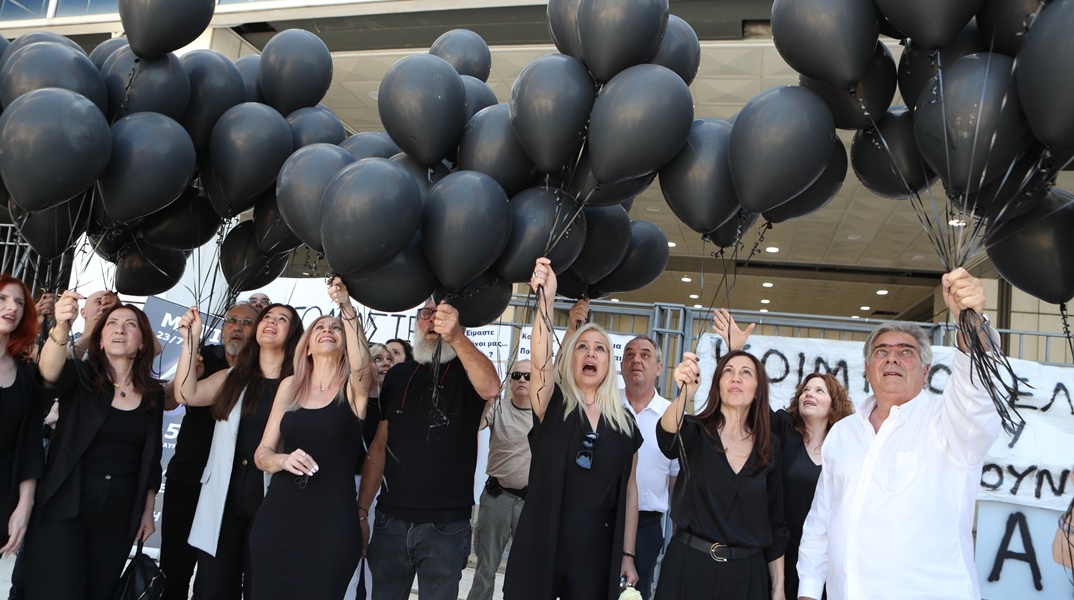 Συγγενείς θυμάτων και εγκαυματιών κρατούν μαύρα μπαλόνια έξω από το Εφετείο Αθηνών 