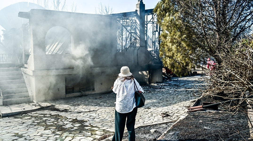 Γυναίκα μπροστά από καμένο σπίτι στην Παλαιά Φώκαια