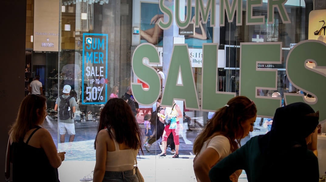 Πολίτες κοιτούν βιτρίνες με εκπτωτικές προσφορές