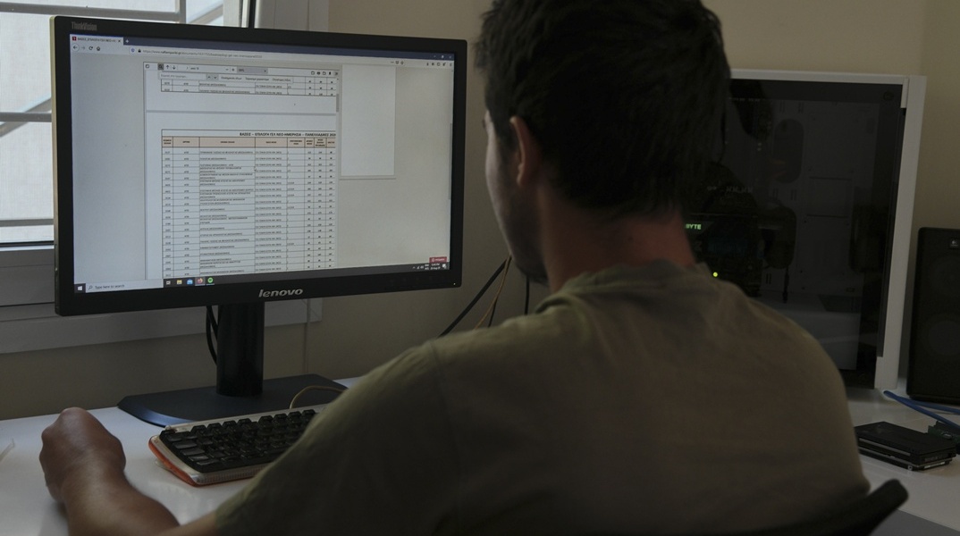 Άτομο που κοιτά βάσεις Πανελληνίων 2025 στον υπολογιστή του