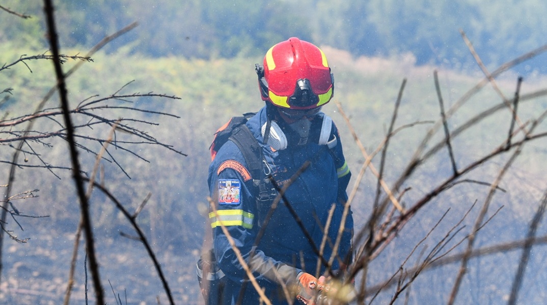 Πυροσβέστης με τη μάνικα ανά χείρας επιχειρεί για την κατάσβεσης φωτιάς