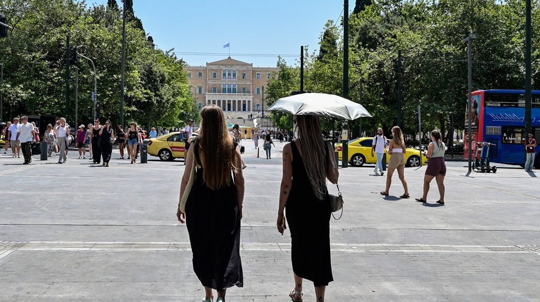 Γυναίκες με ομπρέλες προστατεύονται από τον ήλιο εν μέσω καύσωνα