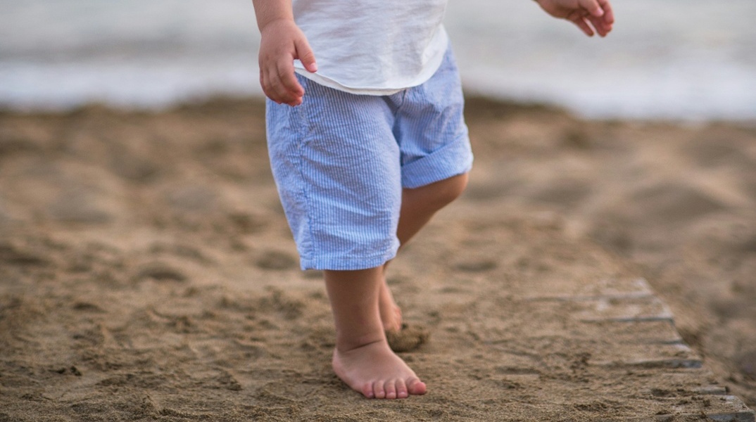 Πόδια παιδιού που περπατά στην άμμο