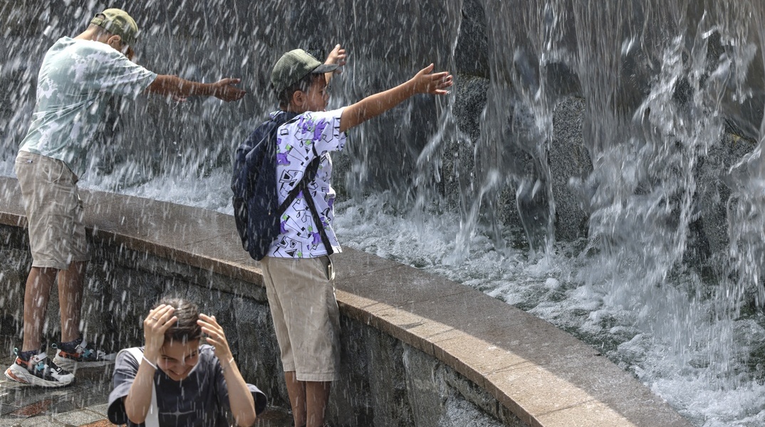 Άτομα αναζητούν λίγες στιγμές δροσιάς σε σιντριβάνι